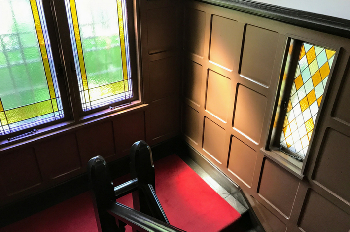 山本有三記念館の2Fへのぼる階段、ステンドグラスをはめ込まれた窓